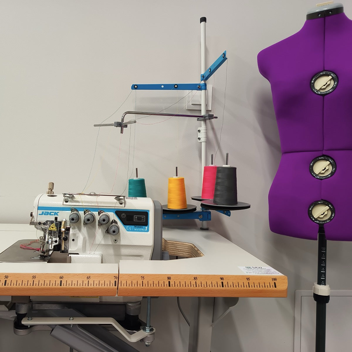 Overlock z kolorowymi szpulkami nici i fioletowy manekin krawiecki w pracowni SELVARRY